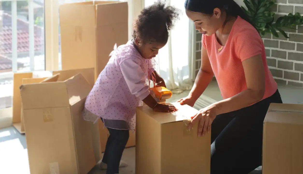 Mutter und Kind packen Kartons für den Umzug. Gemeinsames Sorgerecht und ein neues Zuhause.