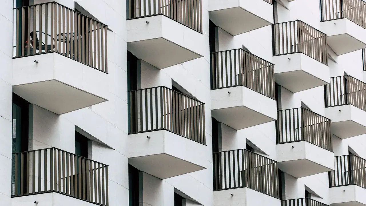 Moderne Fassade mit vielen Balkonen. Ein Tisch und Stuhl auf einem Balkon deuten auf eine mögliche Sperrfrist Eigenbedarf hin.