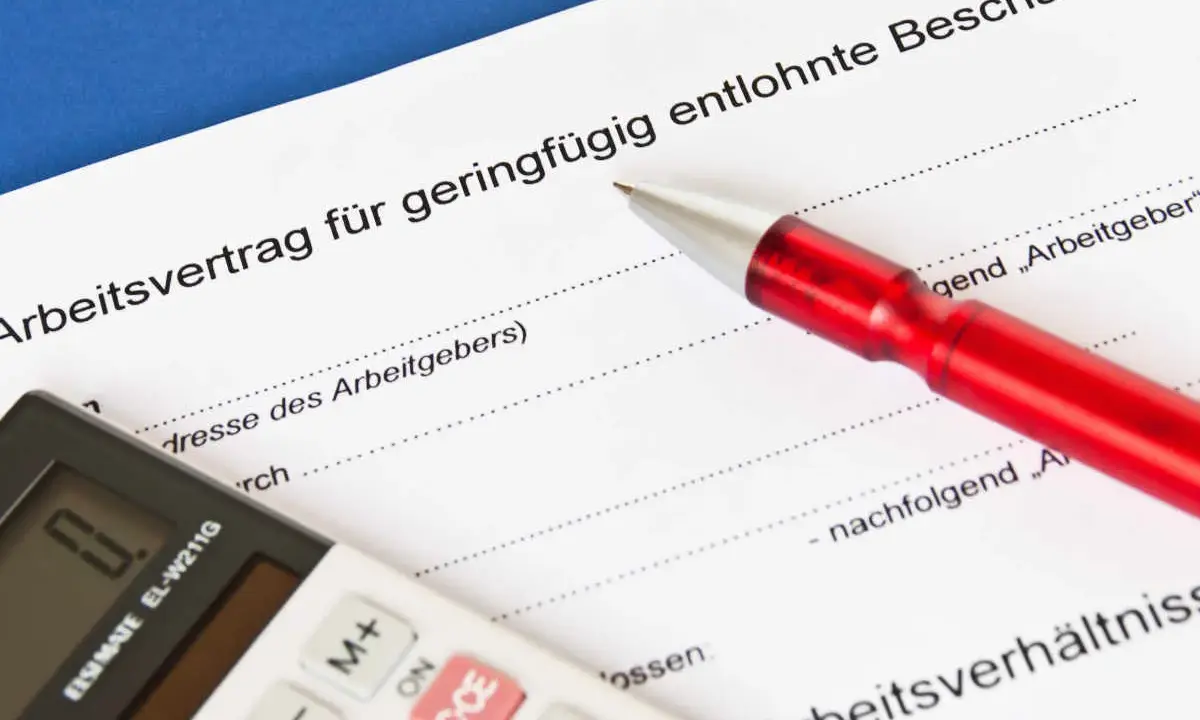 Arbeitsvertrag für geringfügig entlohnte Beschäftigte. Ein roter Stift liegt auf dem Dokument, eine Taschenrechner daneben. Ein 650 Euro Job wird hier geregelt.