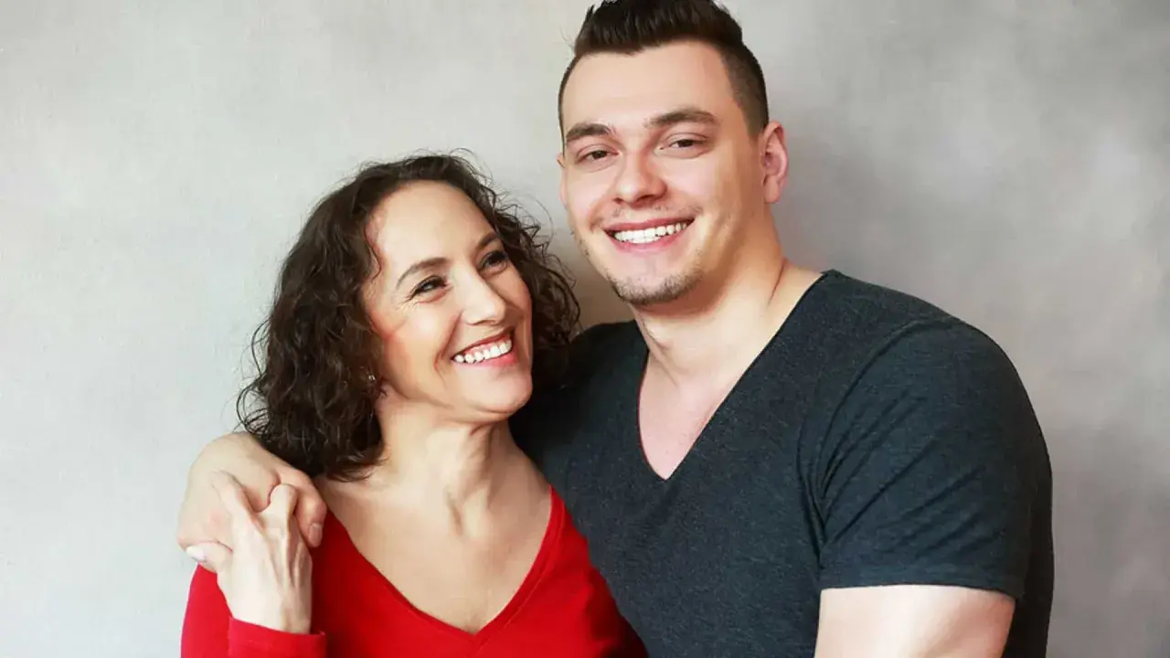 Glückliche Mutter und ihr erwachsener Sohn, der noch zu Hause wohnt. Sie lachen und umarmen sich.
