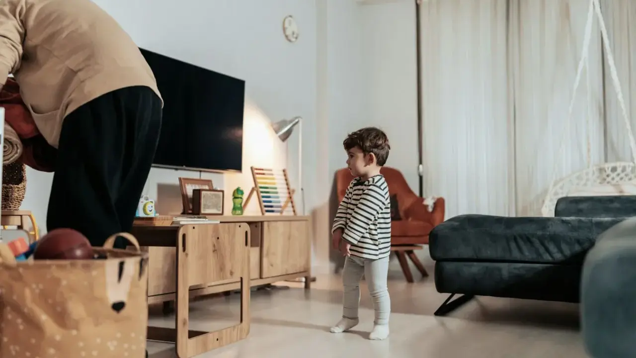Kind steht allein im Wohnzimmer. Die Wohnung ist zu teuer nach einer Trennung.