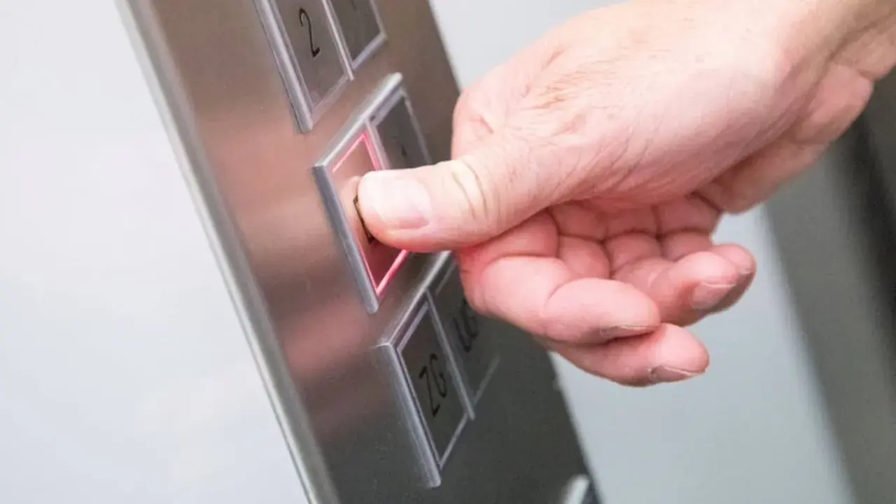 Da der Aufzug defekt ist, drückt die Hand den Knopf für die Mietminderung.