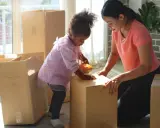 Mutter und Kind packen Kartons für den Umzug. Gemeinsames Sorgerecht und ein neues Zuhause.