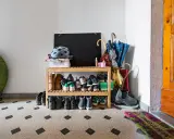 Schuhregal mit vielen Schuhen, Helmen und Regenschirmen im Treppenhaus eines Mehrfamilienhauses.