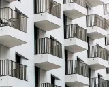 Moderne Fassade mit vielen Balkonen. Ein Tisch und Stuhl auf einem Balkon deuten auf eine mögliche Sperrfrist Eigenbedarf hin.