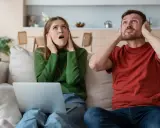 Genervtes Paar auf dem Sofa, Hände an den Ohren. Seit die Mittagsruhe BW abgeschafft ist, ist es hier nie mehr ruhig.