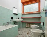 Altes Bad mit türkisen Fliesen, Wanne, Waschbecken, Toilette und Bidet. Hier stellt sich die Frage, wann muss Vermieter Bad renovieren?