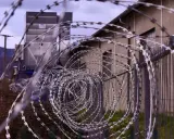 Stacheldraht vor einem Gebäude. Ein Haftbefehl erlassen wegen Unterhaltspflichtverletzung könnte hier eine Rolle spielen.