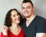 Glückliche Mutter und ihr erwachsener Sohn, der noch zu Hause wohnt. Sie lachen und umarmen sich.