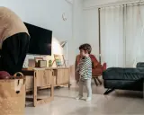 Kind steht allein im Wohnzimmer. Die Wohnung ist zu teuer nach einer Trennung.