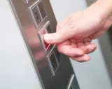 Da der Aufzug defekt ist, drückt die Hand den Knopf für die Mietminderung.