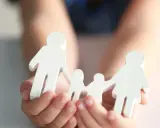 Hände halten weiße Figuren einer Familie. Mögliche Nachteile beim gemeinsamen Sorgerecht werden hier symbolisch dargestellt.