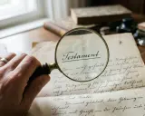 Lupe über einem Testament, der Name des Erben im Testament falsch geschrieben.
