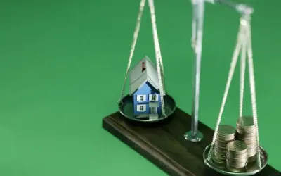 Waage mit Haus und Münzen. Nach einer Scheidung muss eine Hausfrau oft neu planen: Krankenversicherung, Haus und Finanzen neu ordnen.