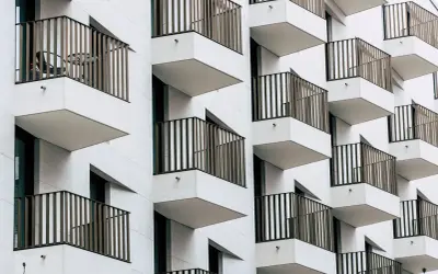 Moderne Fassade mit vielen Balkonen. Ein Tisch und Stuhl auf einem Balkon deuten auf eine mögliche Sperrfrist Eigenbedarf hin.