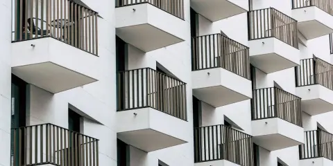 Moderne Fassade mit vielen Balkonen. Ein Tisch und Stuhl auf einem Balkon deuten auf eine mögliche Sperrfrist Eigenbedarf hin.