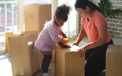 Mutter und Kind packen Kartons für den Umzug. Gemeinsames Sorgerecht und ein neues Zuhause.
