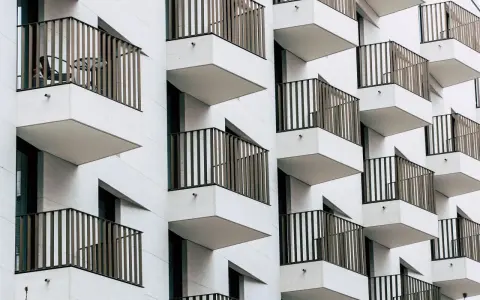 Moderne Fassade mit vielen Balkonen. Ein Tisch und Stuhl auf einem Balkon deuten auf eine mögliche Sperrfrist Eigenbedarf hin.