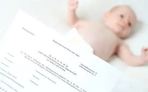 Urkunde zur Vaterschaftsanerkennung liegt neben einem Baby. Die Kosten dafür sind oft gering.