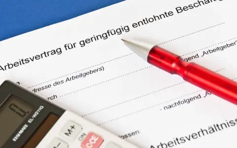 Arbeitsvertrag für geringfügig entlohnte Beschäftigte. Ein roter Stift liegt auf dem Dokument, eine Taschenrechner daneben. Ein 650 Euro Job wird hier geregelt.