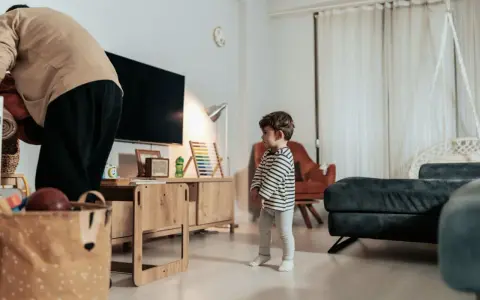 Kind steht allein im Wohnzimmer. Die Wohnung ist zu teuer nach einer Trennung.