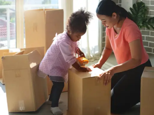 Mutter und Kind packen Kartons für den Umzug. Gemeinsames Sorgerecht und ein neues Zuhause.