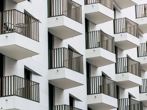 Moderne Fassade mit vielen Balkonen. Ein Tisch und Stuhl auf einem Balkon deuten auf eine mögliche Sperrfrist Eigenbedarf hin.