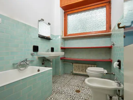 Altes Bad mit türkisen Fliesen, Wanne, Waschbecken, Toilette und Bidet. Hier stellt sich die Frage, wann muss Vermieter Bad renovieren?