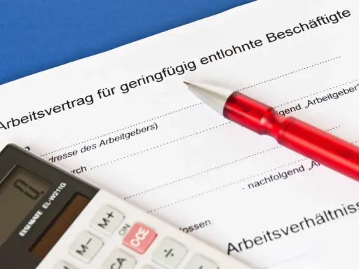 Arbeitsvertrag für geringfügig entlohnte Beschäftigte. Ein roter Stift liegt auf dem Dokument, eine Taschenrechner daneben. Ein 650 Euro Job wird hier geregelt.