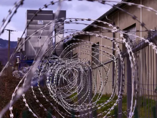 Stacheldraht vor einem Gebäude. Ein Haftbefehl erlassen wegen Unterhaltspflichtverletzung könnte hier eine Rolle spielen.