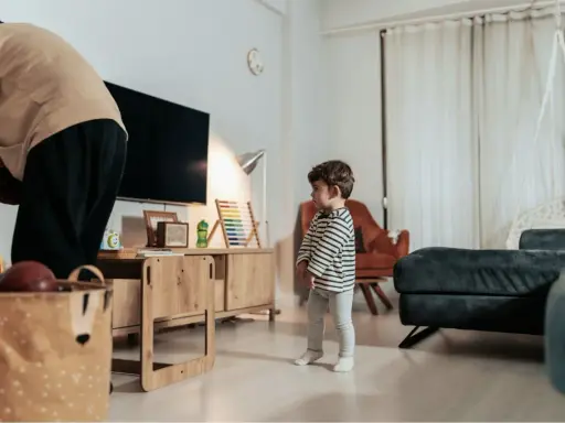 Kind steht allein im Wohnzimmer. Die Wohnung ist zu teuer nach einer Trennung.