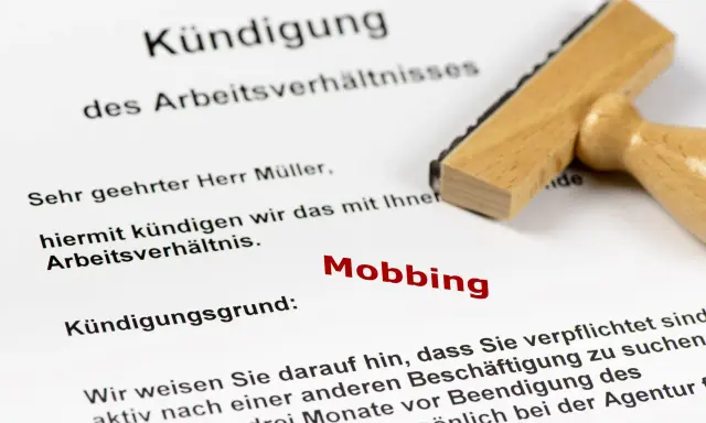 Kündigungsschreiben mit dem Grund "Mobbing". Ein Stempel liegt daneben. Dies kann zu einer Krankschreibung führen.