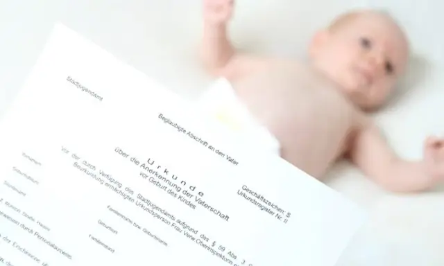 Urkunde zur Vaterschaftsanerkennung liegt neben einem Baby. Die Kosten dafür sind oft gering.