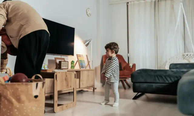 Kind steht allein im Wohnzimmer. Die Wohnung ist zu teuer nach einer Trennung.