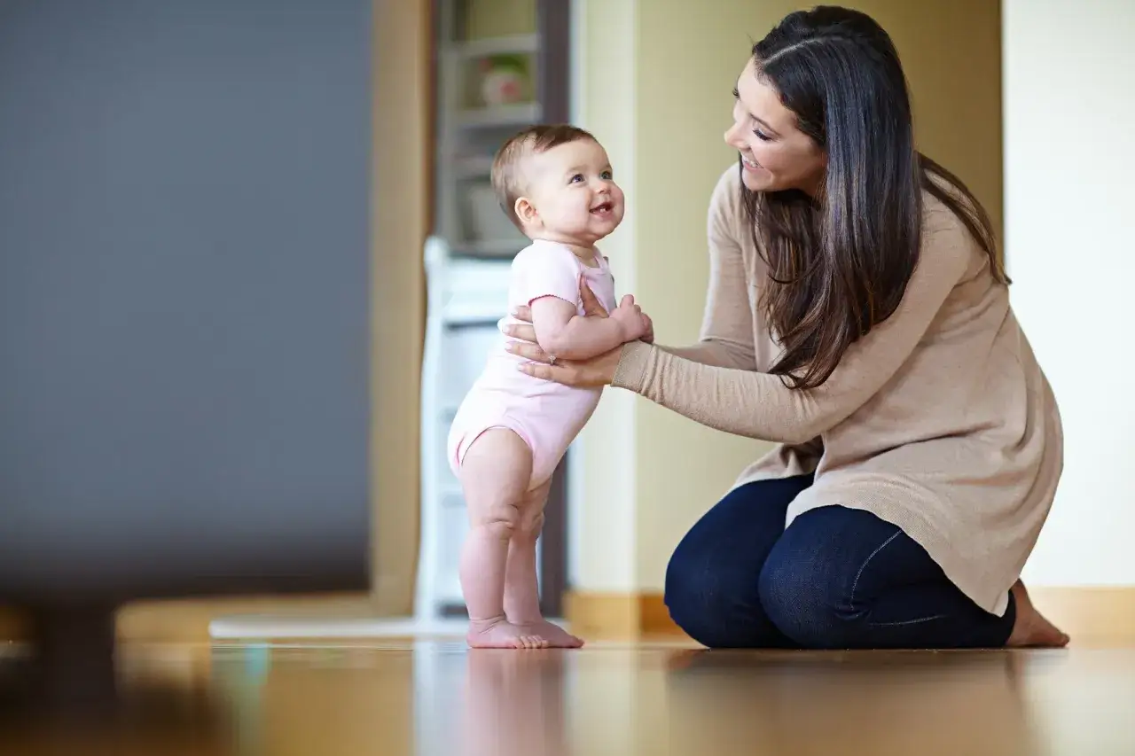 Mutter hilft Baby beim Stehen. Nach der Trennung ist die Wohnung zu teuer, aber die Liebe zum Kind bleibt.