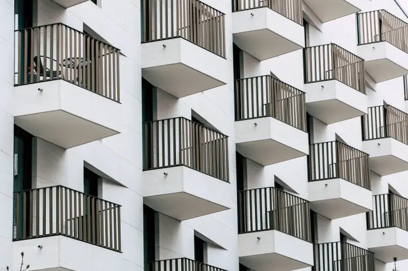 Moderne Fassade mit vielen Balkonen. Ein Tisch und Stuhl auf einem Balkon deuten auf eine mögliche Sperrfrist Eigenbedarf hin.